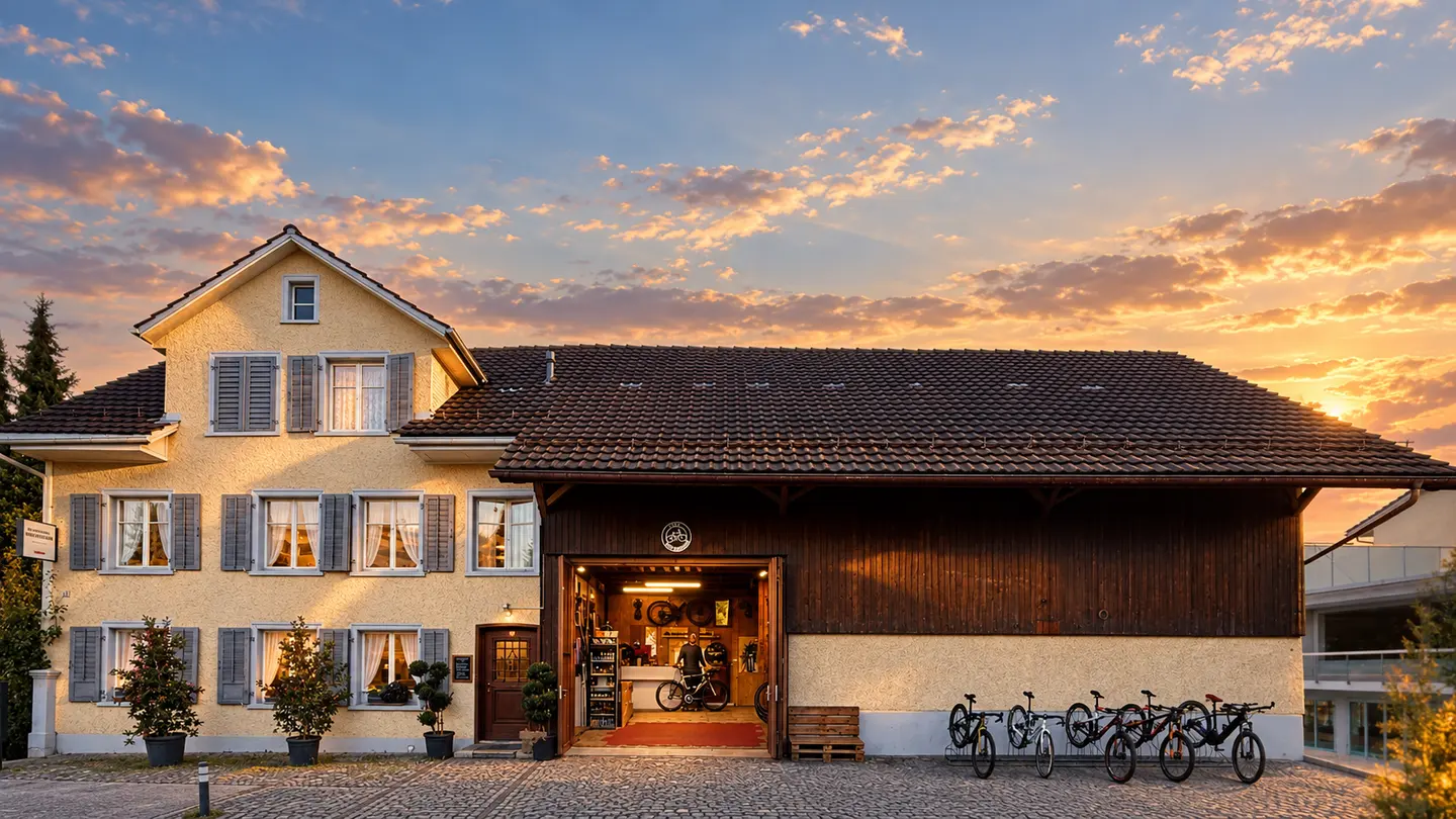 Die Velowerkstatt von aussen im Abendlicht: offenes Tor, davor eine Reihe Velos